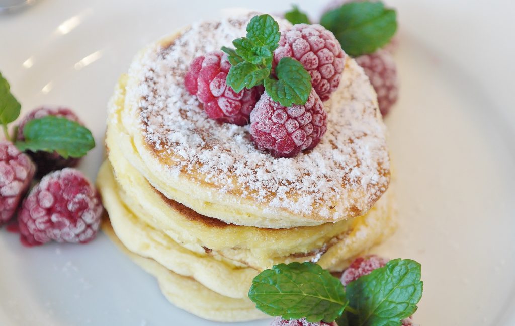 Stack of pancakes with raspberries and green leaves